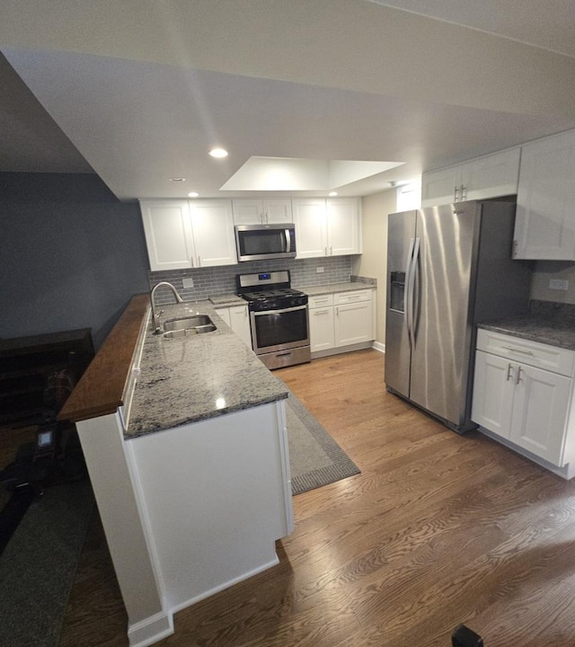 8201 Daniel Dr, Justice, IL 60458 - kitchen with stainless steel appliances, a peninsula, white cabinetry, backsplash, and light wood-style floors