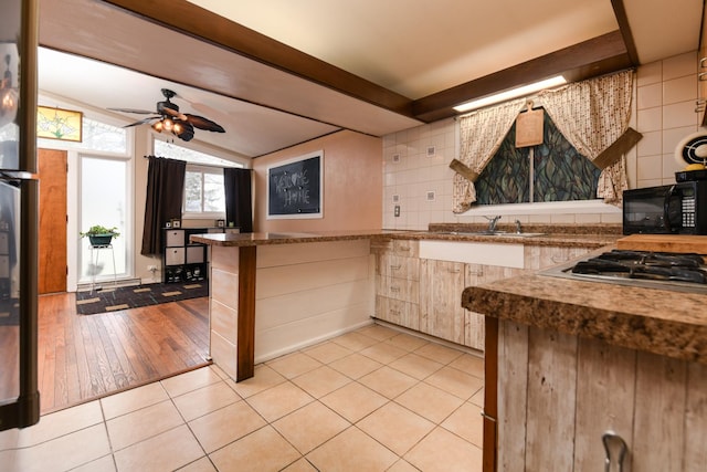 144 Crestwood Dr, East Dundee, IL 60118 - kitchen featuring black microwave, a peninsula, stainless steel gas cooktop, ceiling fan, and light tile patterned floors