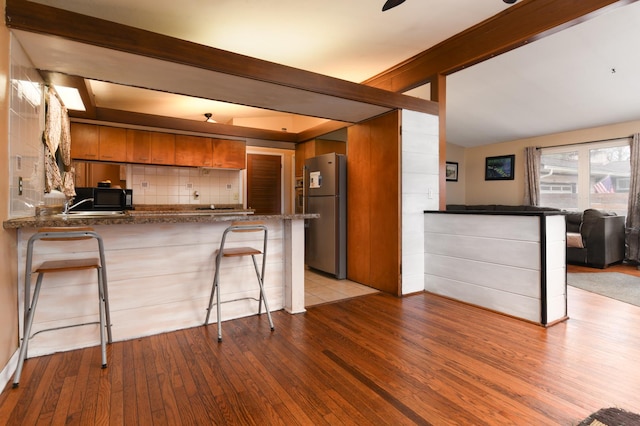 144 Crestwood Dr, East Dundee, IL 60118 - kitchen with freestanding refrigerator, brown cabinetry, a peninsula, backsplash, and light wood finished floors