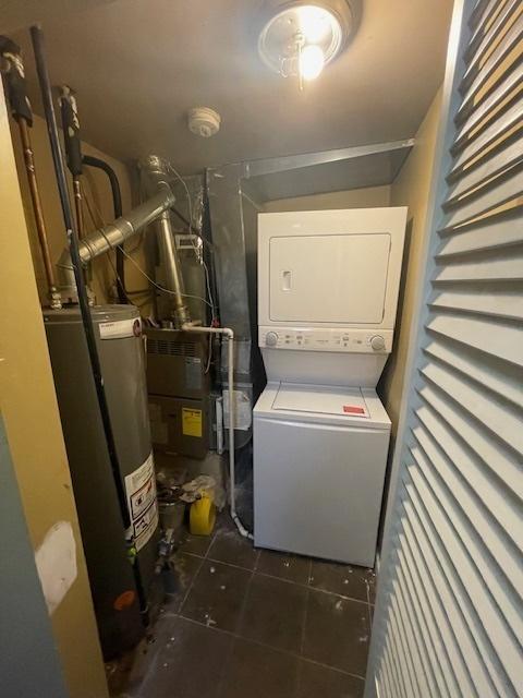 2620 W 24th St, Chicago, IL 60608 - laundry room with stacked washing machine and dryer, gas water heater, and dark tile patterned floors