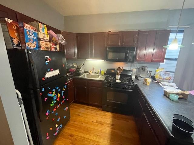 2620 W 24th St, Chicago, IL 60608 - kitchen with black appliances, light wood-style floors, and hanging light fixtures