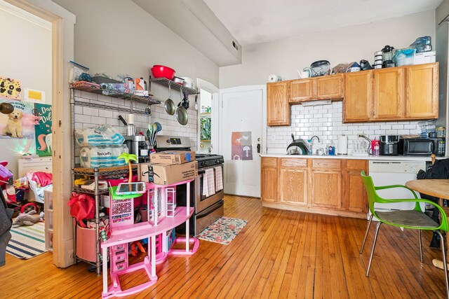 1624 N Oakley Ave, Chicago, IL 60647 - kitchen featuring stainless steel gas range oven, black microwave, decorative backsplash, light wood-style flooring, and light countertops