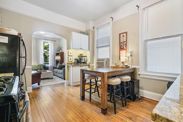 1624 N Oakley Ave, Chicago, IL 60647 - kitchen featuring arched walkways, gas range, light wood-style floors, white cabinets, and cooling unit