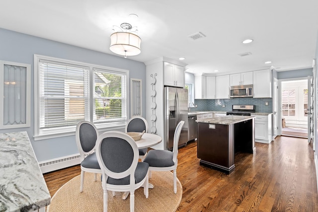 15 E Fairview St, Arlington Heights, IL 60005 - kitchen with appliances with stainless steel finishes, a baseboard heating unit, a center island, dark wood-type flooring, and decorative backsplash