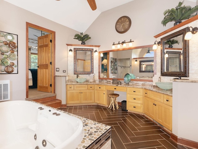 12114 W Castle Dr, Mokena, IL 60448 - bathroom featuring lofted ceiling, double vanity, a tub with jets, ceiling fan, and tasteful backsplash