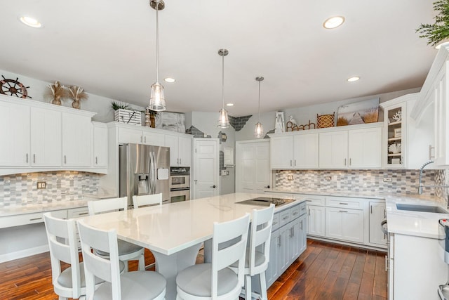 12114 W Castle Dr, Mokena, IL 60448 - kitchen featuring stainless steel appliances, decorative backsplash, dark wood-style flooring, a kitchen island, and white cabinets