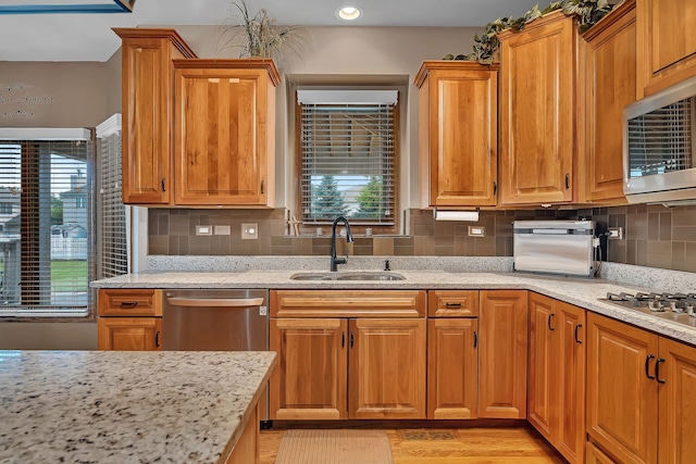 26645 W Ian Ct, Channahon, IL 60410 - kitchen featuring appliances with stainless steel finishes, light stone countertops, backsplash, light wood-type flooring, and brown cabinets