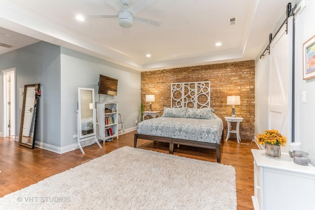 4336 N Troy St, Chicago, IL 60618 - bedroom featuring a barn door, wood finished floors, a tray ceiling, brick wall, and recessed lighting