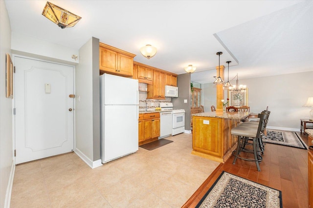 110 W Butterfield Rd Unit 314S, Elmhurst, IL 60126 - kitchen with white appliances, a breakfast bar, backsplash, pendant lighting, and a kitchen island