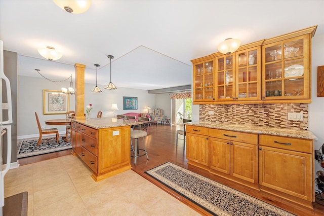 110 W Butterfield Rd Unit 314S, Elmhurst, IL 60126 - kitchen featuring a breakfast bar area, light stone counters, backsplash, brown cabinets, and open floor plan