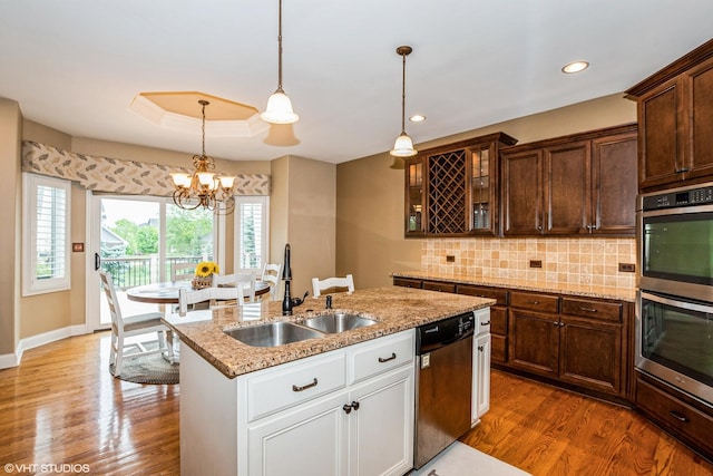 21409 Foxtail Dr, Mokena, IL 60448 - kitchen featuring appliances with stainless steel finishes, wood finished floors, glass insert cabinets, a kitchen island with sink, and tasteful backsplash