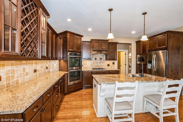 21409 Foxtail Dr, Mokena, IL 60448 - kitchen with appliances with stainless steel finishes, a breakfast bar area, light wood-style flooring, tasteful backsplash, and recessed lighting