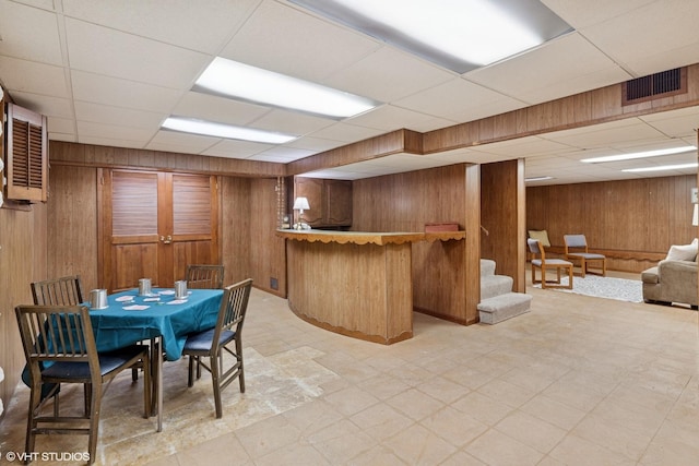 1329 Sanford Ln, Glenview, IL 60025 - dining area featuring wooden walls, a drop ceiling, light floors, a dry bar, and stairs