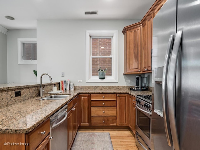 669 N Peoria St Unit 1N, Chicago, IL 60642 - kitchen featuring appliances with stainless steel finishes, brown cabinetry, light stone counters, and a peninsula