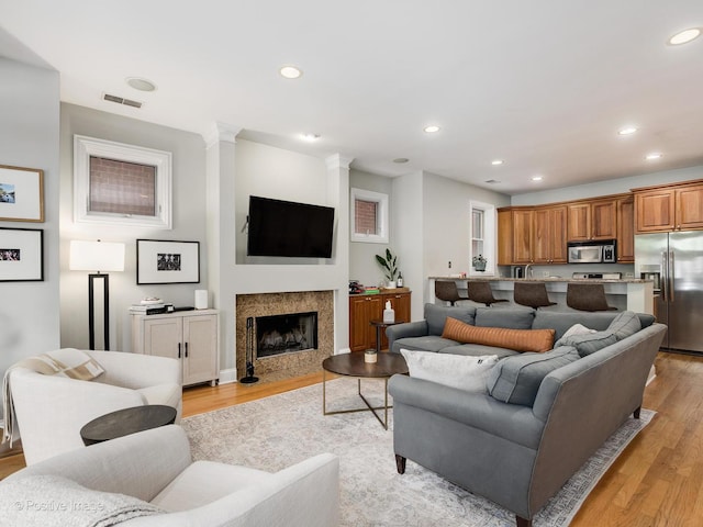 669 N Peoria St Unit 1N, Chicago, IL 60642 - living area featuring light wood-type flooring, recessed lighting, ornate columns, and a high end fireplace
