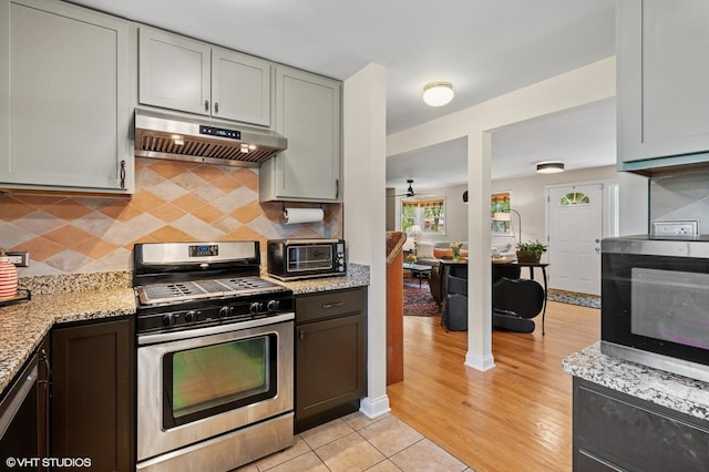 2417 Lyons St, Evanston, IL 60201 - kitchen with appliances with stainless steel finishes, range hood, decorative backsplash, light stone countertops, and light wood-style flooring