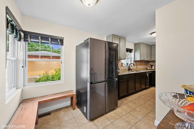 2417 Lyons St, Evanston, IL 60201 - kitchen featuring freestanding refrigerator, light tile patterned flooring, light stone countertops, and black dishwasher