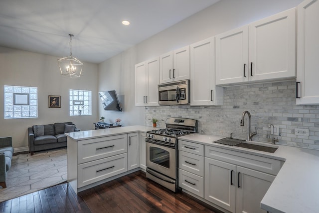 1349 W Huron St Unit 1, Chicago, IL 60642 - kitchen featuring appliances with stainless steel finishes, a peninsula, light countertops, a chandelier, and tasteful backsplash
