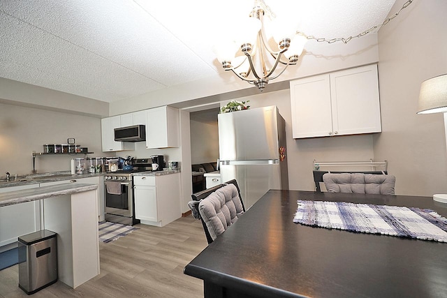 4946 Douglas Rd Unit 202, Downers Grove, IL 60515 - kitchen featuring stainless steel appliances, a chandelier, white cabinetry, light wood-type flooring, and a textured ceiling
