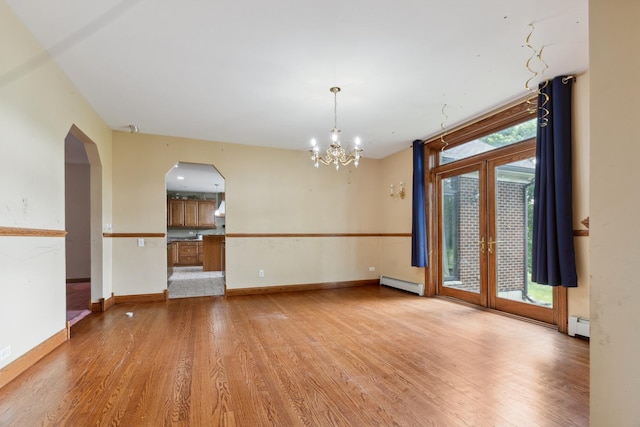 1313 Plum Tree Rd, Barrington Hills, IL 60010 - empty room with a baseboard heating unit, light wood-style flooring, a chandelier, and arched walkways