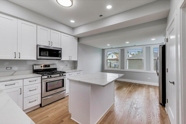 5735 S Fairfield Ave, Chicago, IL 60629 - kitchen featuring stainless steel appliances, white cabinetry, light wood finished floors, light stone countertops, and a kitchen island