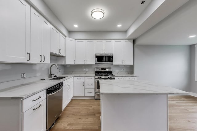 5735 S Fairfield Ave, Chicago, IL 60629 - kitchen with stainless steel appliances, light wood finished floors, a center island, white cabinets, and light stone countertops