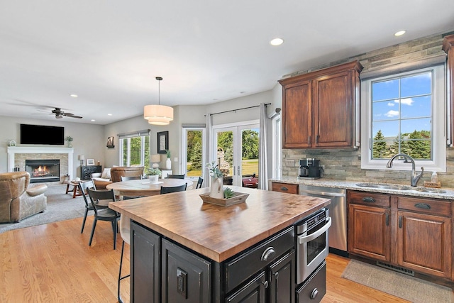 29990 Fehmarn Way, Genoa, IL 60135 - kitchen featuring dishwasher, a stone fireplace, light wood-type flooring, open floor plan, and wood counters