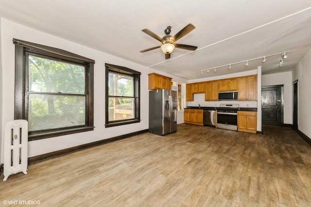 1455 E 56th St Unit 1E, Chicago, IL 60637 - kitchen with appliances with stainless steel finishes, radiator heating unit, dark countertops, wood finished floors, and a ceiling fan