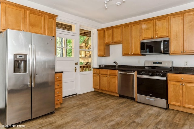 1455 E 56th St Unit 1E, Chicago, IL 60637 - kitchen featuring appliances with stainless steel finishes, wood finished floors, brown cabinetry, and dark stone countertops