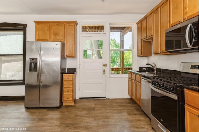1455 E 56th St Unit 1E, Chicago, IL 60637 - kitchen with appliances with stainless steel finishes, dark wood finished floors, brown cabinetry, and dark stone counters