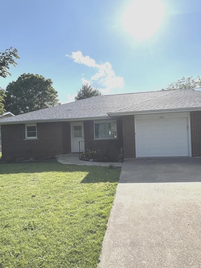 422 N 4th St, Cissna Park, IL 60924 - ranch-style home with driveway, brick siding, an attached garage, a front yard, and a shingled roof