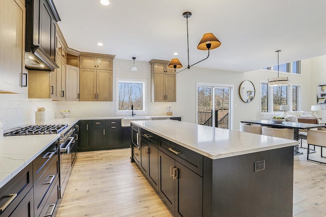 1104 Walter St, Lemont, IL 60439 - kitchen with a kitchen island, stainless steel stove, light wood-style floors, decorative backsplash, and light stone countertops