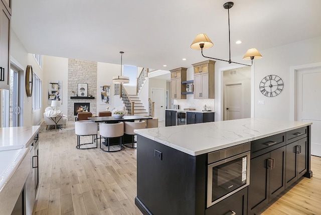 1104 Walter St, Lemont, IL 60439 - kitchen featuring stainless steel microwave, a fireplace, light wood-style floors, open floor plan, and backsplash