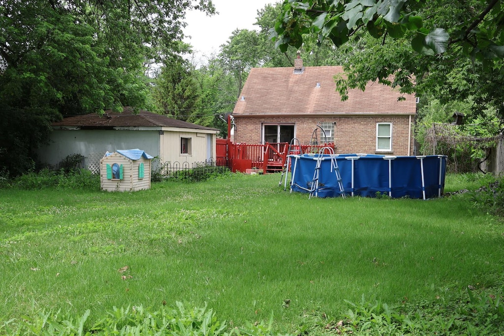 6807 S 79th Ave, Bridgeview, IL 60455 - view of grassy yard with an outdoor pool, a wooden deck, and an outdoor structure