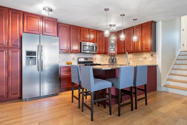 1024 Inverrary Ln Unit 1024, Deerfield, IL 60015 - kitchen featuring stainless steel appliances, light wood-style flooring, light stone counters, and hanging light fixtures