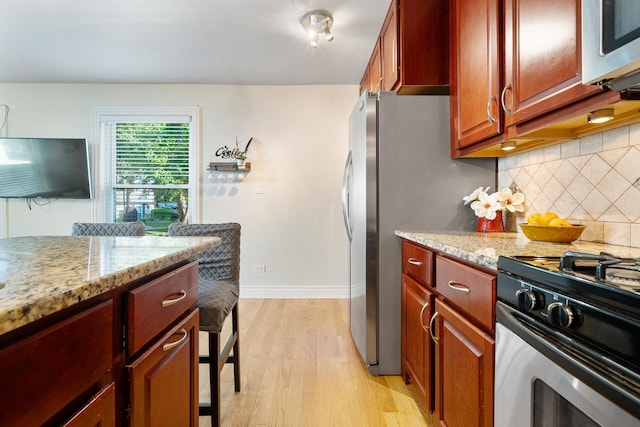 1024 Inverrary Ln Unit 1024, Deerfield, IL 60015 - kitchen featuring appliances with stainless steel finishes, light wood-style flooring, tasteful backsplash, and light stone counters