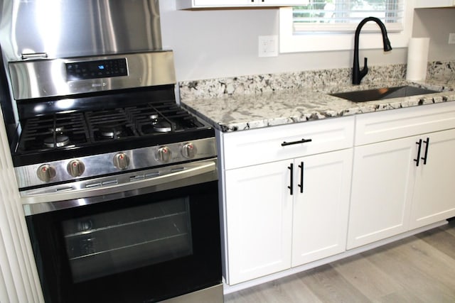 3042 Bar Harbour Rd, Aurora, IL 60504 - kitchen with stainless steel gas range oven, light wood-style floors, light stone countertops, and white cabinets