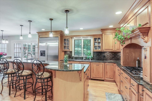 1490 S Ridge Rd, Lake Forest, IL 60045 - kitchen featuring appliances with stainless steel finishes, a kitchen bar, a center island with sink, backsplash, and glass insert cabinets