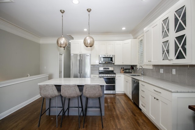 323 W Schiller St Unit 1W, Chicago, IL 60610 - kitchen with stainless steel appliances, a breakfast bar area, a center island, ornamental molding, and white cabinets