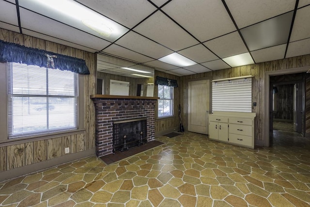 1128 Shiloh Blvd, Zion, IL 60099 - unfurnished living room with stone floors, a paneled ceiling, wood walls, and a fireplace