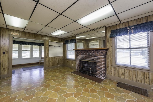 1128 Shiloh Blvd, Zion, IL 60099 - unfurnished living room with a paneled ceiling, stone floors, wooden walls, plenty of natural light, and a fireplace