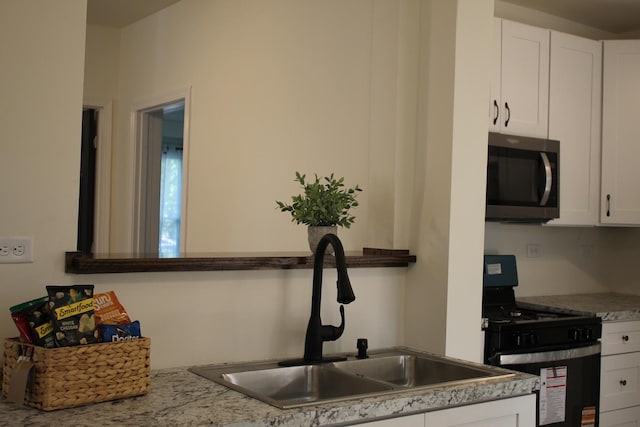 534 Mohawk St, Joliet, IL 60432 - kitchen featuring stainless steel microwave, range with gas stovetop, white cabinets, and light countertops