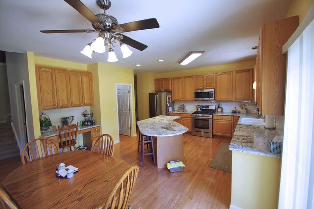 1437 Sage Dr, Bolingbrook, IL 60490 - kitchen with appliances with stainless steel finishes, a center island, light wood finished floors, ceiling fan, and a breakfast bar