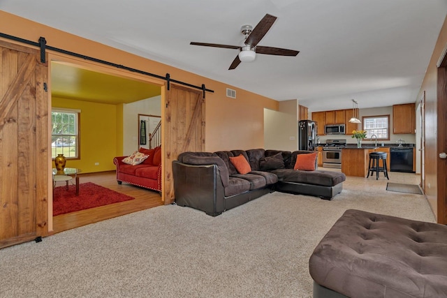 4218 Glenlo Dr, Plainfield, IL 60586 - living room featuring a barn door, ceiling fan, light carpet, and light wood-style floors