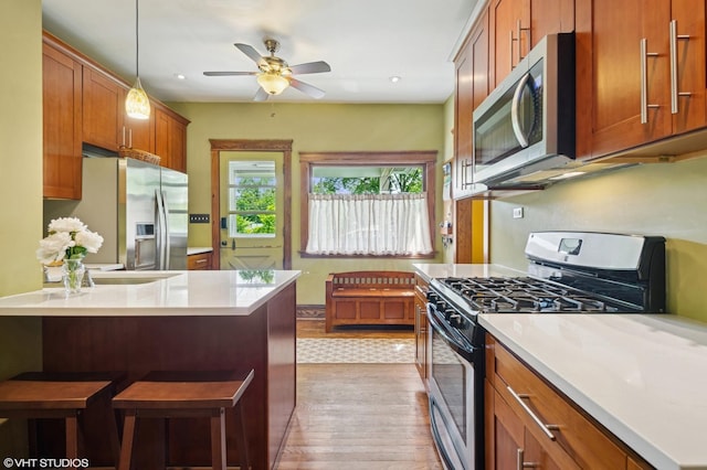 500 Fair Oaks Ave, Oak Park, IL 60302 - kitchen featuring stainless steel appliances, light wood-type flooring, a ceiling fan, brown cabinets, and a kitchen breakfast bar