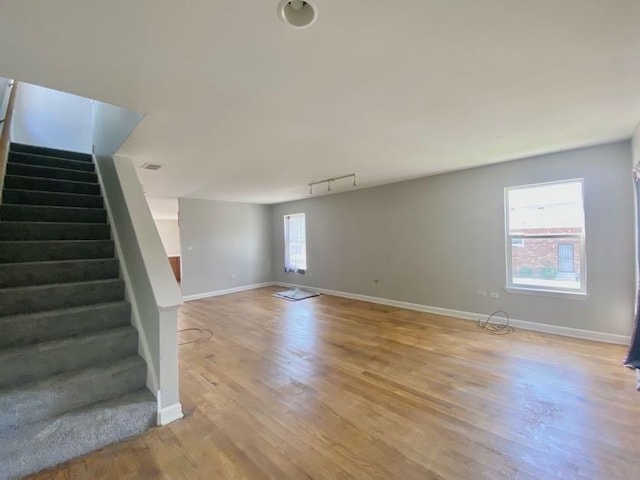 9159 S Dobson Ave, Chicago, IL 60619 - unfurnished living room with stairway, light wood-style floors, and rail lighting