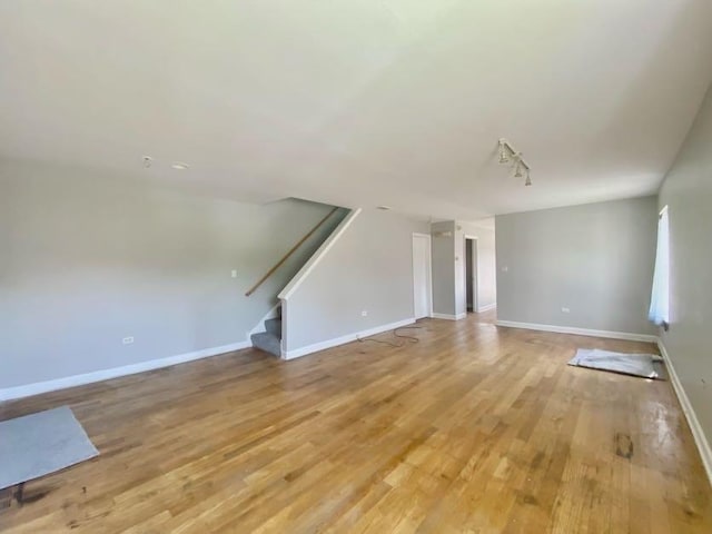 9159 S Dobson Ave, Chicago, IL 60619 - unfurnished living room featuring light wood finished floors, stairs, and track lighting