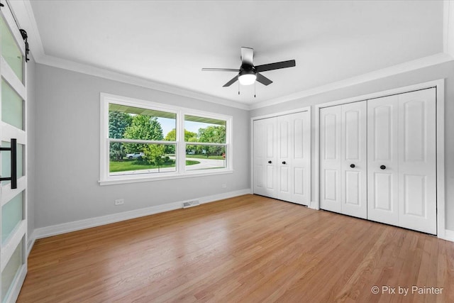 27W075 Fleming Dr, Winfield, IL 60190 - unfurnished bedroom featuring two closets, light wood-type flooring, crown molding, and a ceiling fan