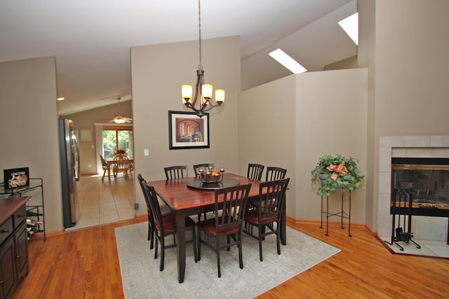 135 Miller Rd, Lake Zurich, IL 60047 - dining area with vaulted ceiling, light wood-style flooring, a chandelier, a tile fireplace, and a skylight