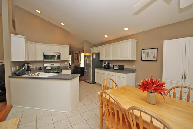135 Miller Rd, Lake Zurich, IL 60047 - kitchen featuring stainless steel appliances, a peninsula, dark countertops, white cabinetry, and lofted ceiling